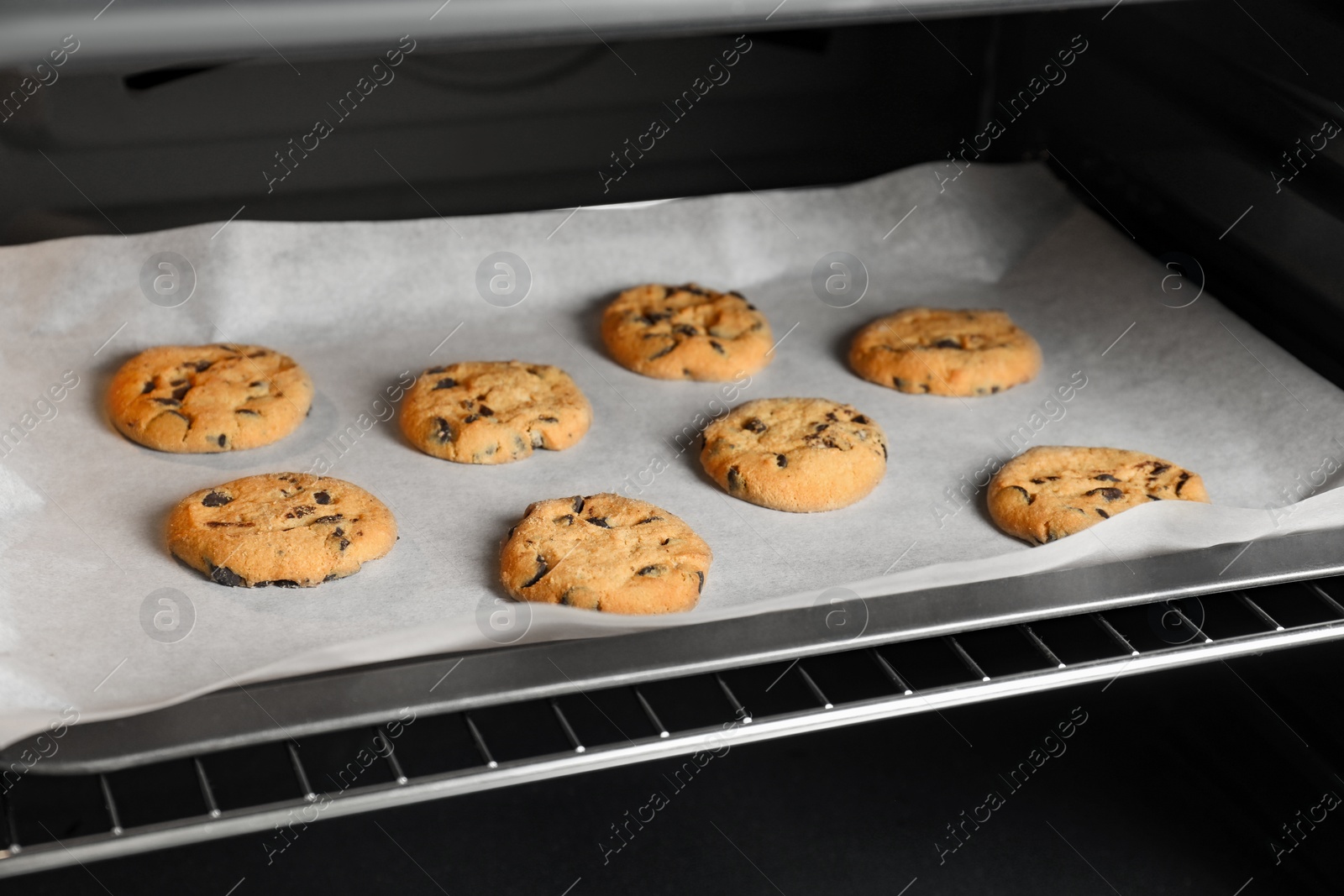 Photo of Baking delicious chocolate chip cookies in oven, closeup