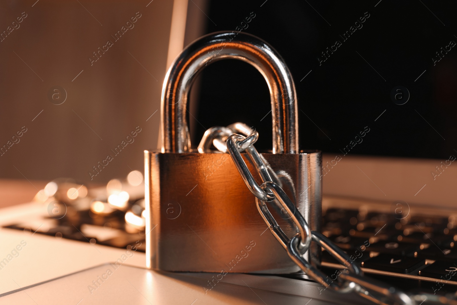 Photo of Cyber security. Laptop with padlock and chain on table, closeup