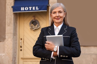 Photo of Smiling business owner with tablet near her hotel outdoors, space for text