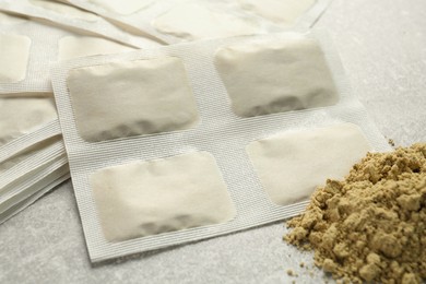 Photo of Mustard powder and plasters on light grey table, closeup