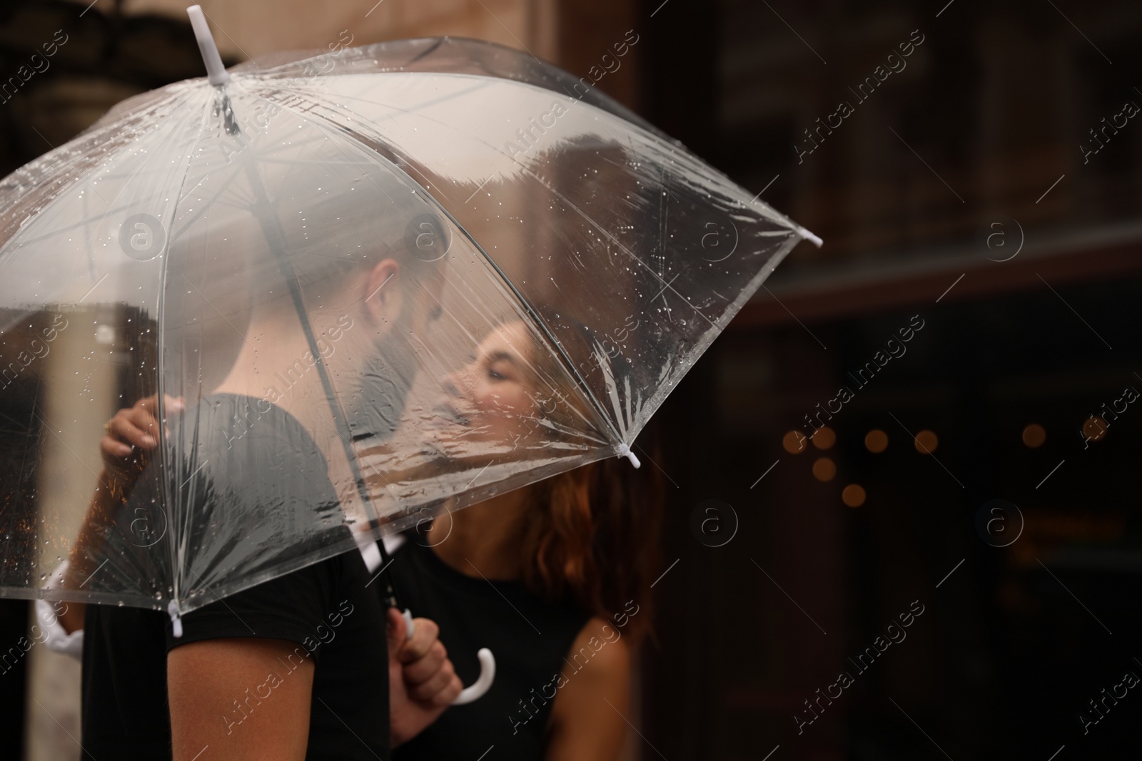 Photo of Young couple with umbrella enjoying time together under rain on city street, space for text