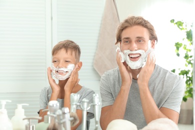 Father and son applying shaving foam in bathroom