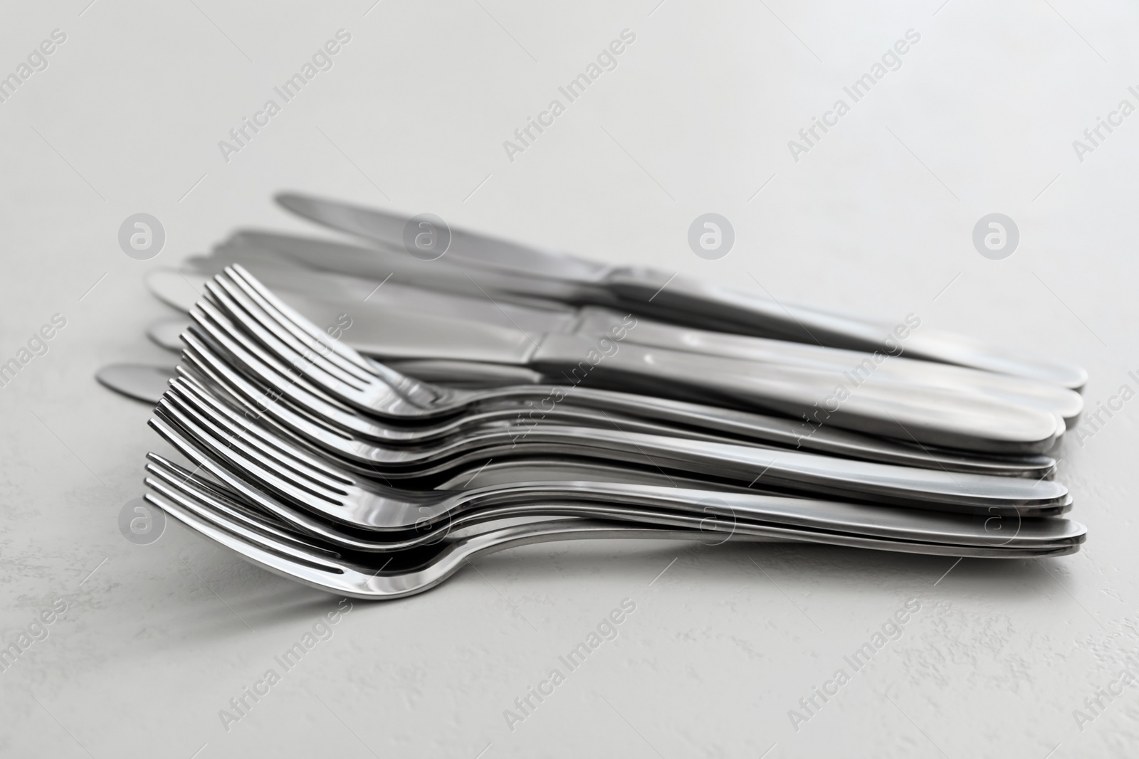 Photo of Knives and forks on white table, closeup