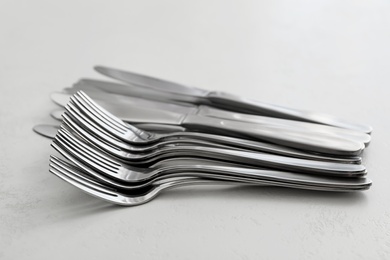 Photo of Knives and forks on white table, closeup