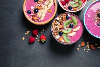 Acai smoothie bowls with granola and fruits on black table, flat lay