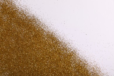 Photo of Shiny golden glitter on white background, top view