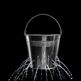 Leaky bucket with water on black background 