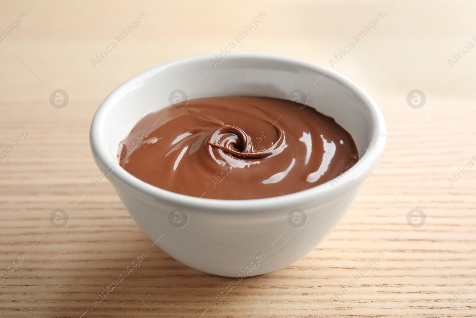 Photo of Bowl with sweet chocolate cream on wooden background