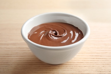 Bowl with sweet chocolate cream on wooden background