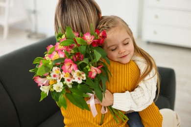 Photo of Little daughter congratulating her mom with bouquet of alstroemeria flowers at home. Happy Mother's Day