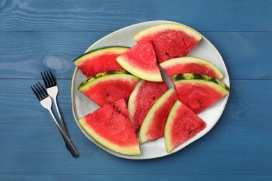 Photo of Plate with slices of juicy watermelon on blue wooden table, top view
