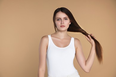 Photo of Young woman with strong healthy hair on beige background