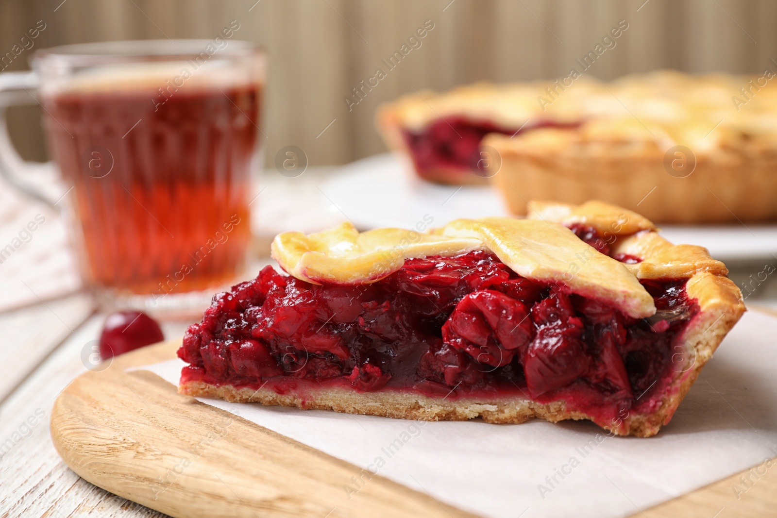 Photo of Slice of delicious fresh cherry pie on wooden board, closeup