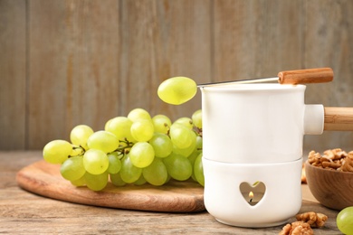 Photo of Fondue pot and grapes on wooden table