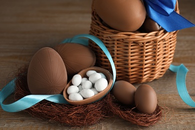 Delicious chocolate Easter eggs and ribbon on wooden table, closeup