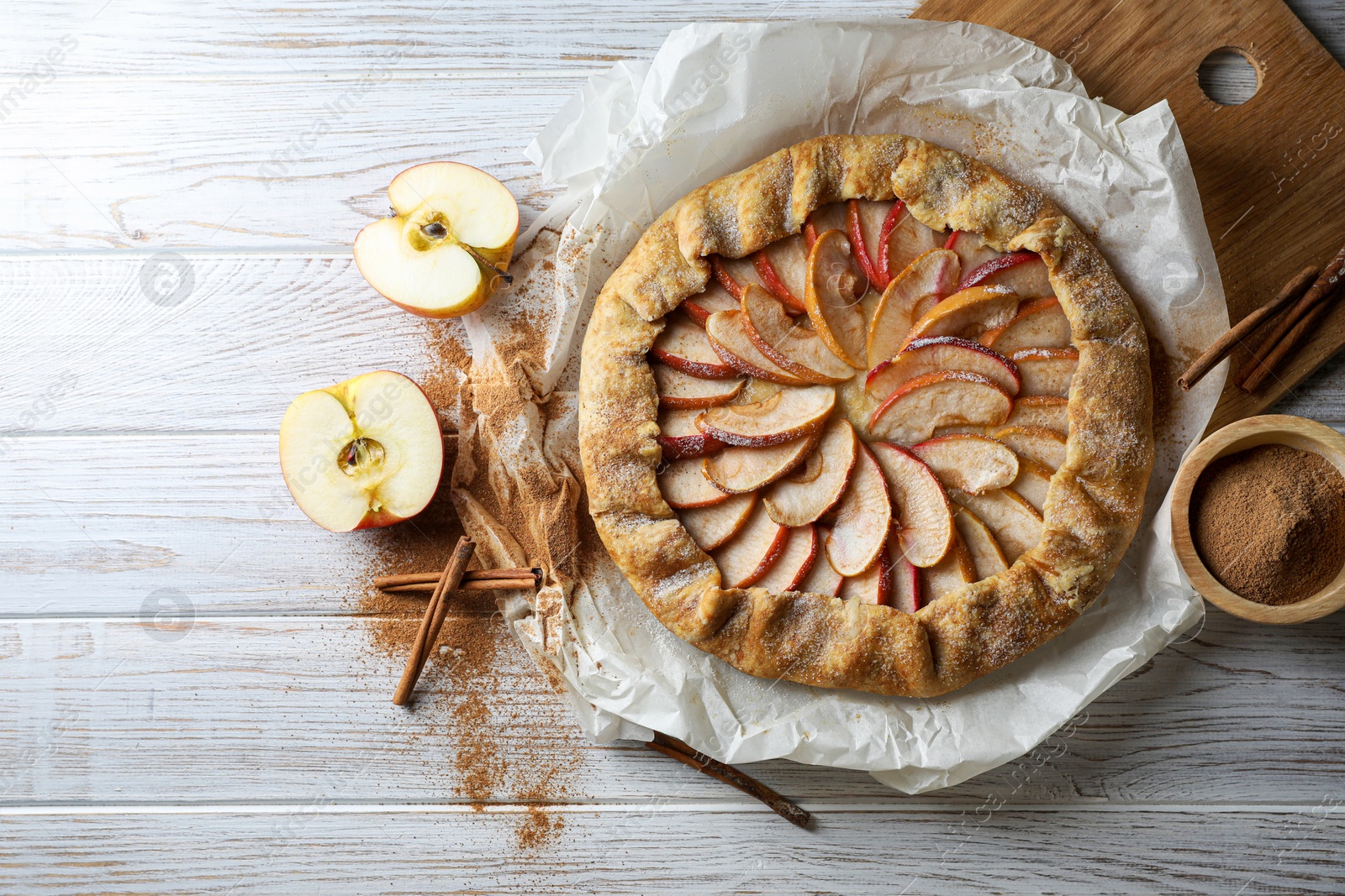 Photo of Delicious apple galette and cinnamon on white wooden table, flat lay