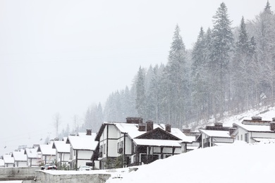Photo of Beautiful view of mountain ski resort with many cottages. Winter vacation
