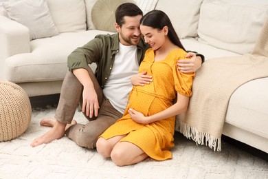 Happy pregnant woman spending time with her husband at home