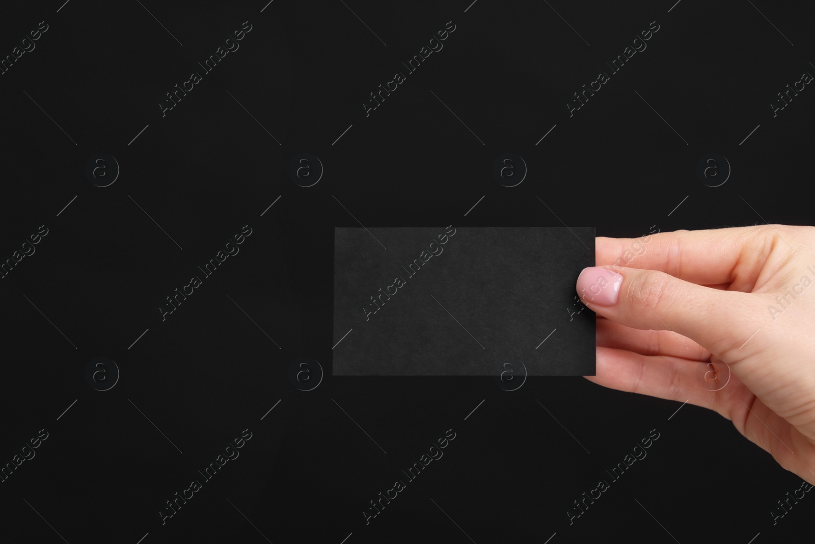 Photo of Woman holding blank business card on black background, closeup. Space for text