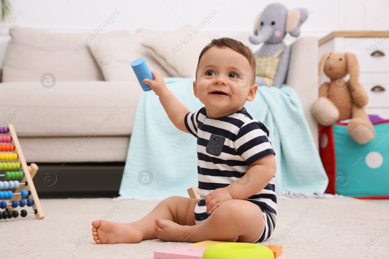 Photo of Cute baby boy playing with toys on floor at home