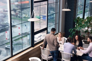 Photo of Group of coworkers having coffee break in cafe, space for text