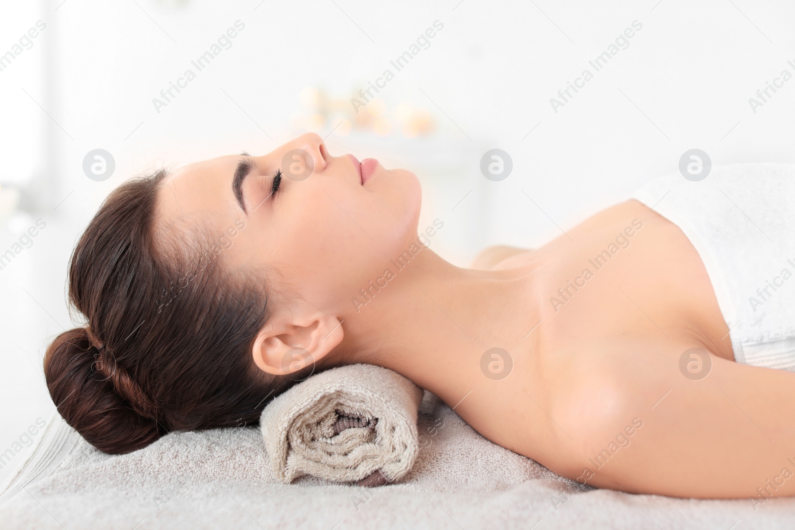 Photo of Young woman lying on massage table in spa salon