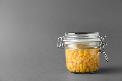 Photo of Jar of pickled sweet corn on grey background. Space for text