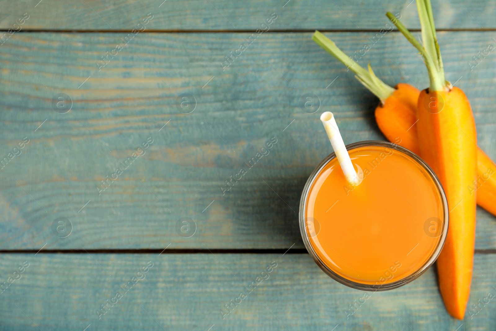 Photo of Freshly made carrot juice on wooden table, flat lay. Space for text