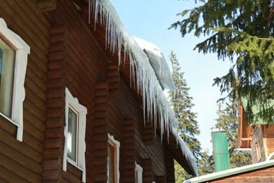 Photo of House with icicles on roof, low angle view. Winter season