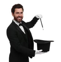 Happy magician showing magic trick with top hat on white background