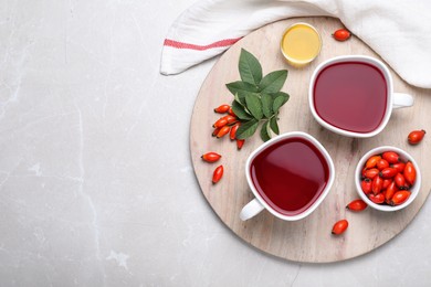 Photo of Fresh rose hip tea and berries on light table, flat lay. Space for text