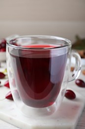 Photo of Glass cup of fresh dogwood tea on white marble board