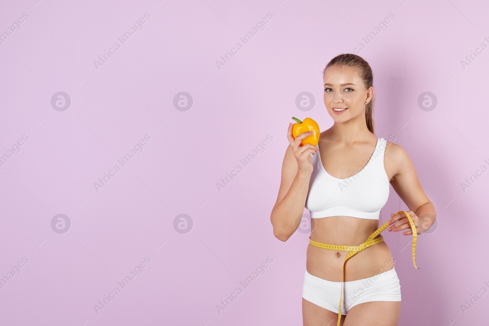 Photo of Young woman with pepper and measuring tape on color background. Healthy diet