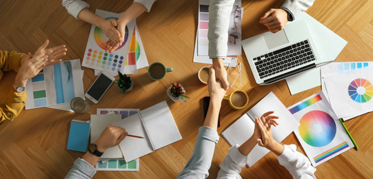 Team of professional designers working together at table, top view