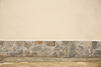 Photo of Beautiful beige wall with stone fragments and concrete floor