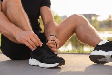 Man tying shoelaces before running outdoors on sunny day, closeup