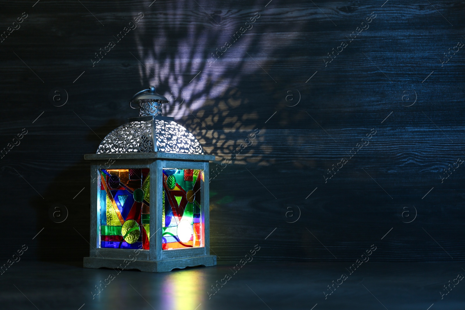 Photo of Decorative Arabic lantern on table against dark background. Space for text