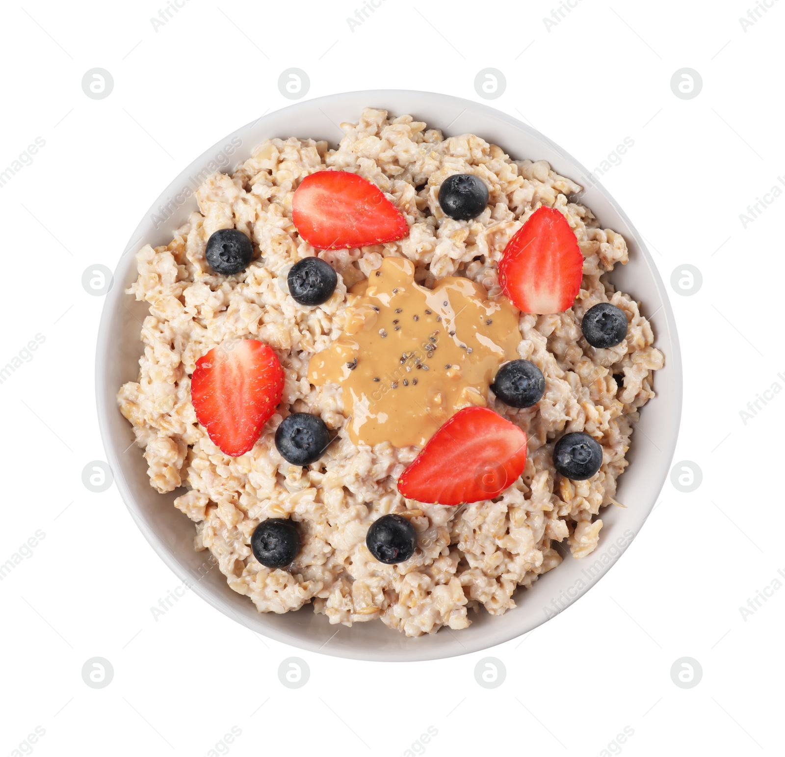 Photo of Tasty boiled oatmeal with berries, chia seeds and peanut butter in bowl isolated on white, top view