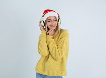 Photo of Happy woman with headphones on light grey background. Christmas music
