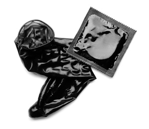 Unrolled black condom and package on white background, top view. Safe sex