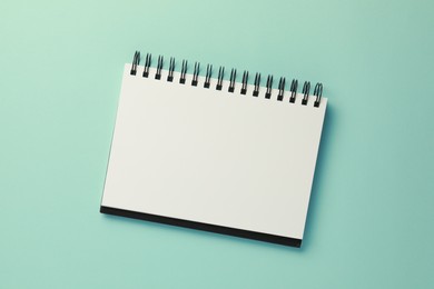 Photo of Blank notebook on turquoise background, top view