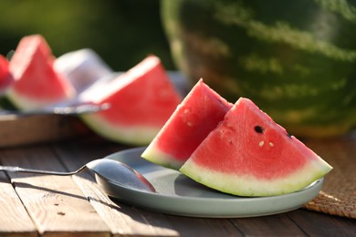 Photo of Slices of tasty ripe watermelon on wooden table outdoors, closeup