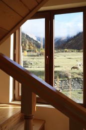 Photo of Beautiful view of picturesque landscape with high mountains from window in cozy room