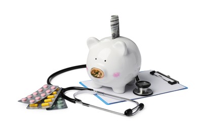 Photo of Piggy bank with money, stethoscope, clipboard and pills on white background. Medical insurance