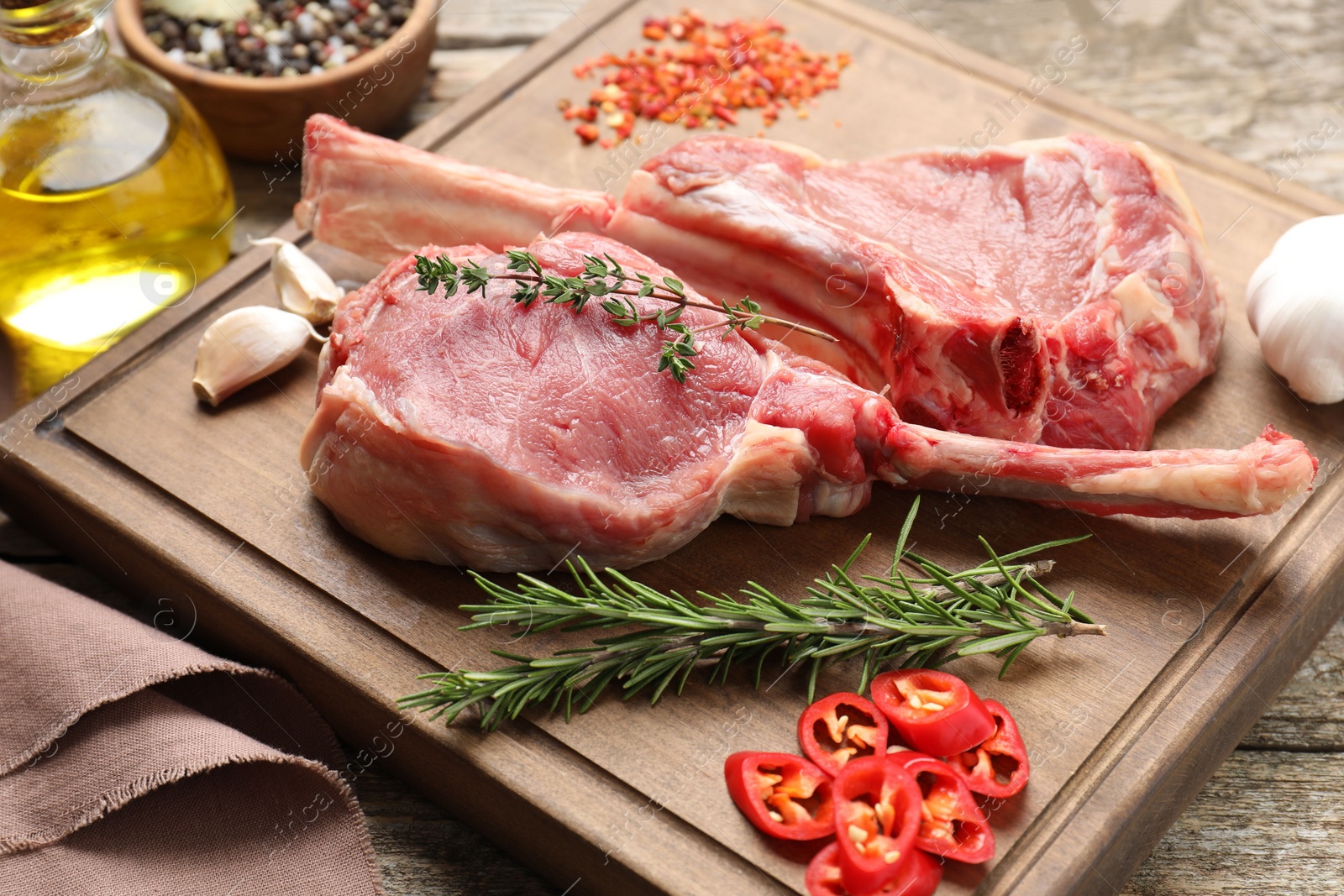 Photo of Fresh tomahawk beef cuts and spices on wooden table