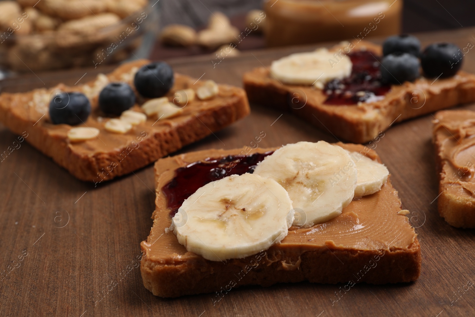 Photo of Different tasty toasts with nut butter and products on table, closeup