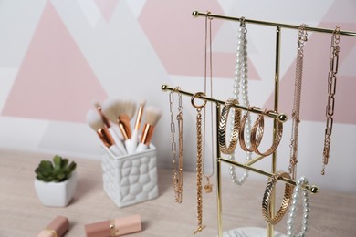 Photo of Holder with set of luxurious jewelry on wooden dressing table