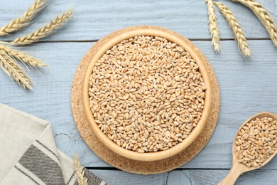 Photo of Ears of wheat and grains on pale light blue wooden table, flat lay