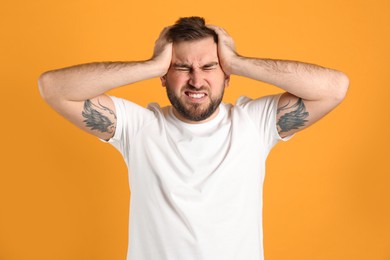 Photo of Man suffering from migraine on yellow background