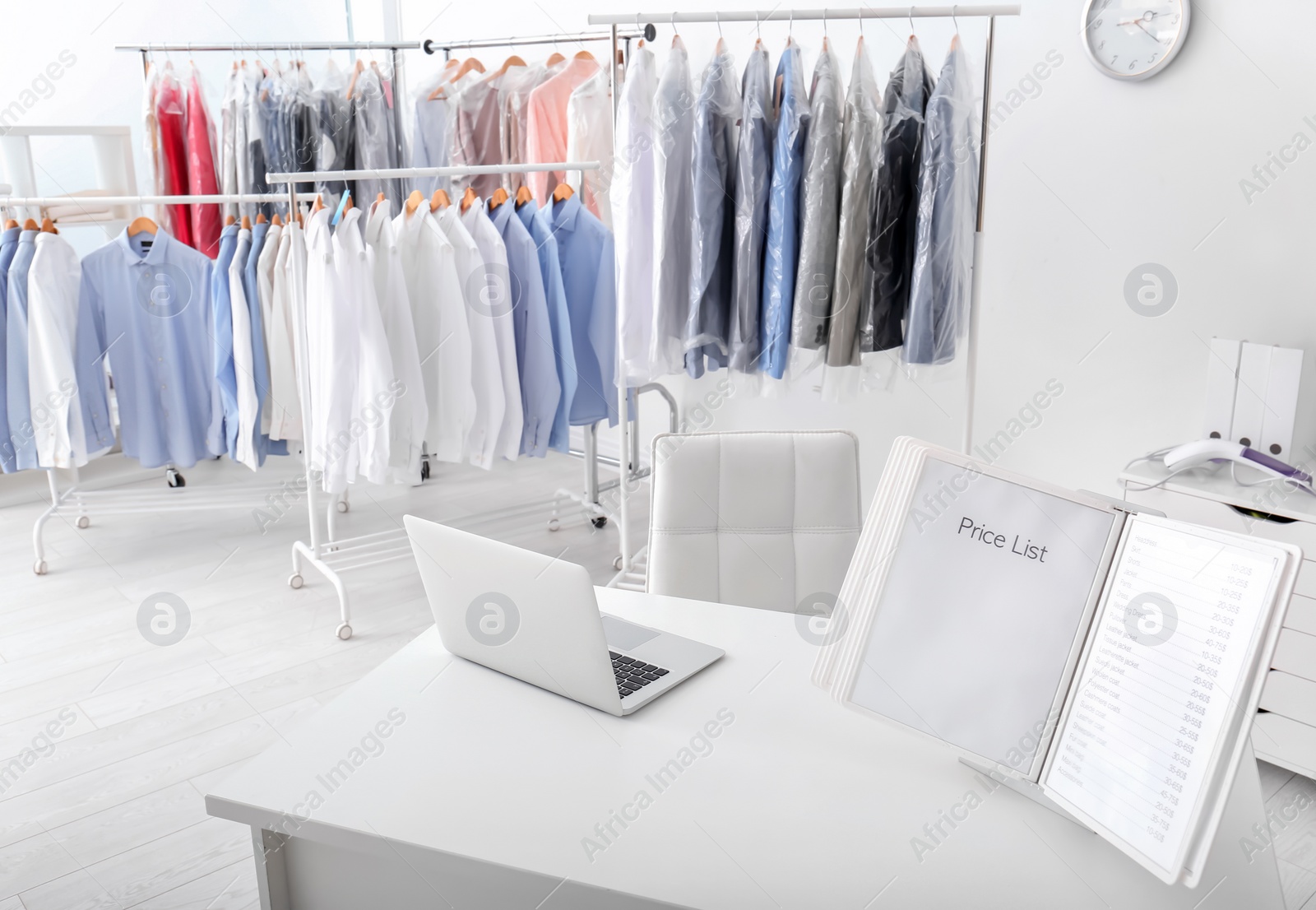 Photo of Workplace of receptionist with laptop and price list at dry-cleaner's